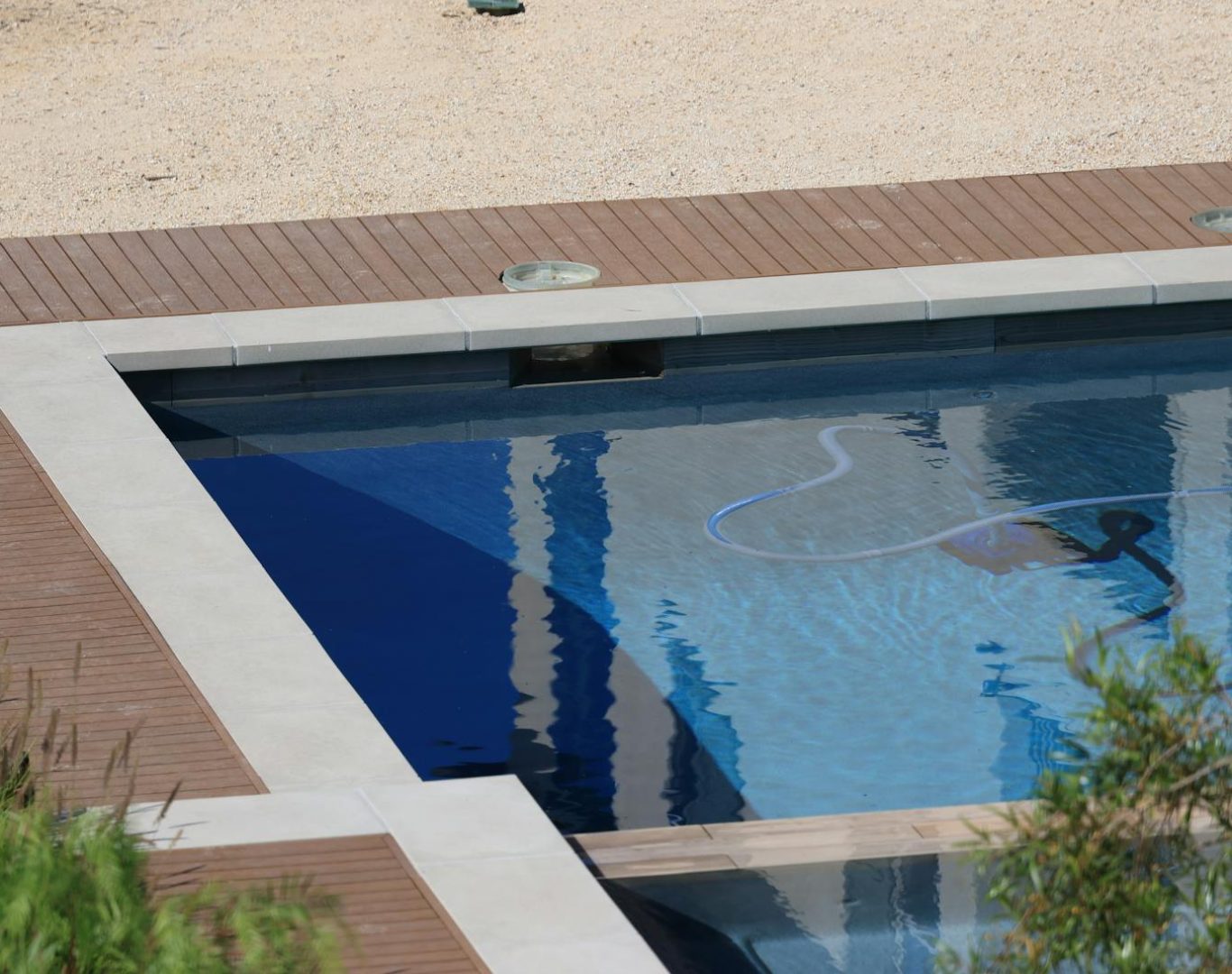 A serene swimming pool with wooden decking and clear blue water on a sunny day.